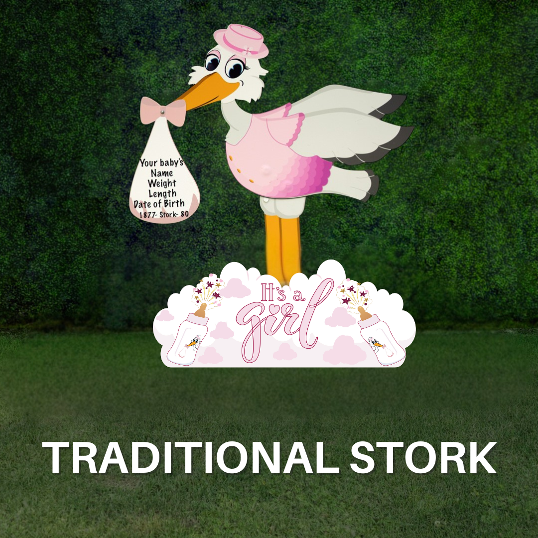 A white and pink stork yard sign holding a bag labeled “It’s a Girl!” standing on grass in front of a green hedge background.